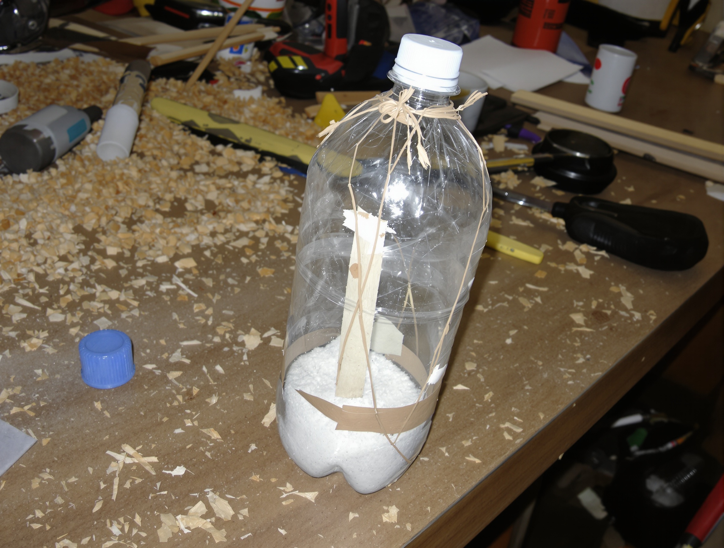 Absorbeur d'humidité DIY fabriqué à partir d'une bouteille en plastique sur un établi en désordre.