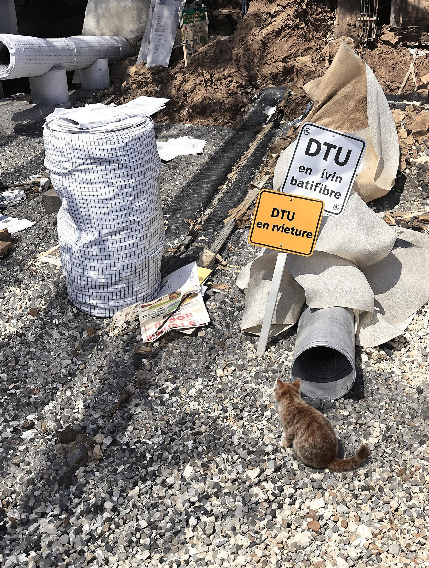 Coin de chantier avec drainage conforme aux normes DTU, tuyaux SN4, géotextile, gravier et chat inspecteur.