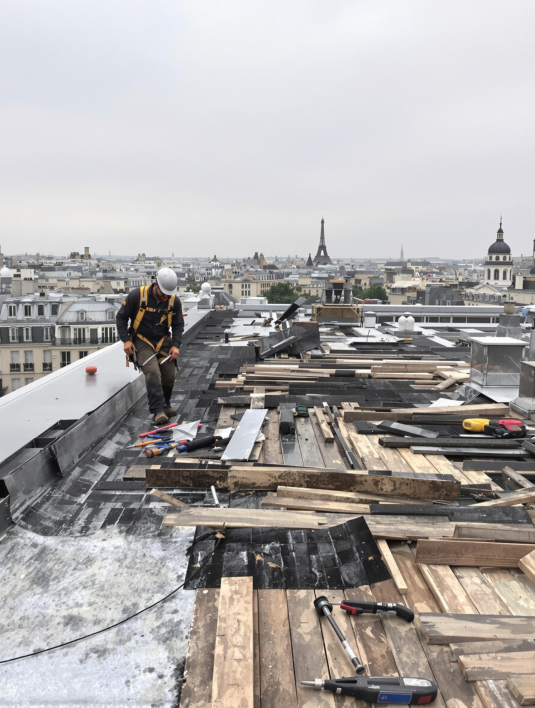 Artisan inspectant une toiture zinc haussmannienne avec condensation et vis inox mal posées.