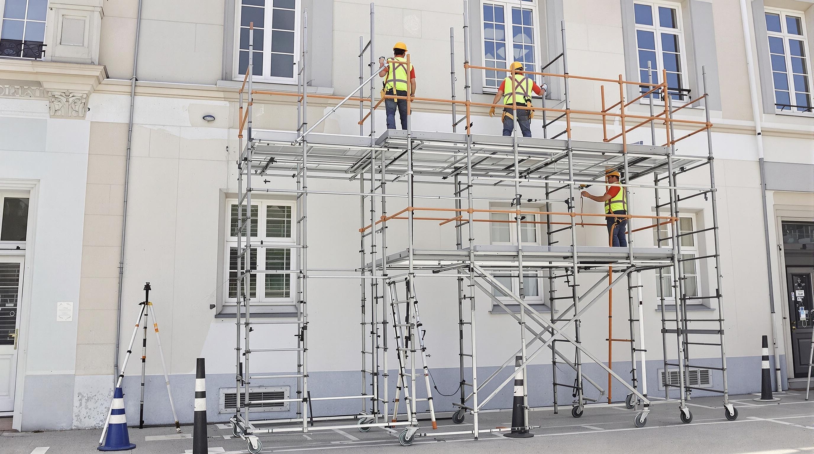 Un échafaudage roulant stable et bien monté, utilisé pour des travaux de peinture extérieure, illustrant une solution plus adaptée pour des travaux d'envergure.