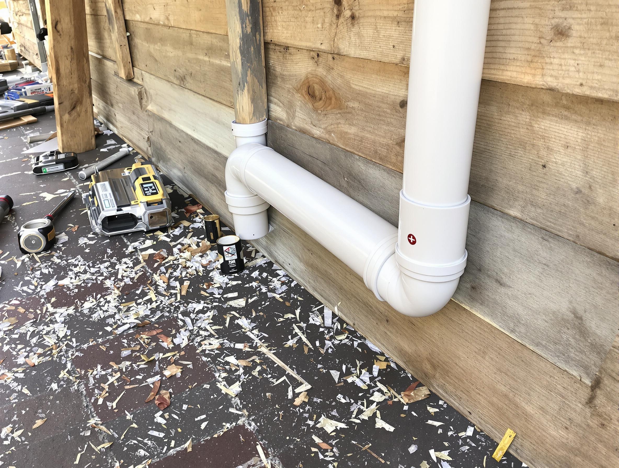 Gouttière DIY en PVC installée sur une cabane en palettes.