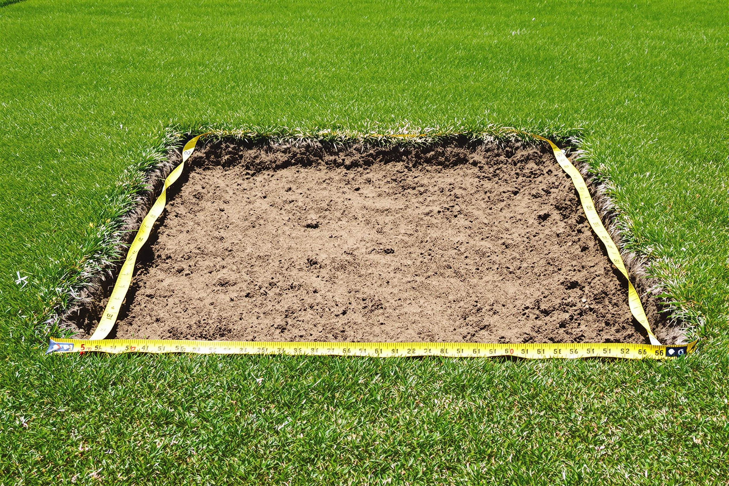 Un mètre ruban posé au sol dans un jardin marquant 5m².