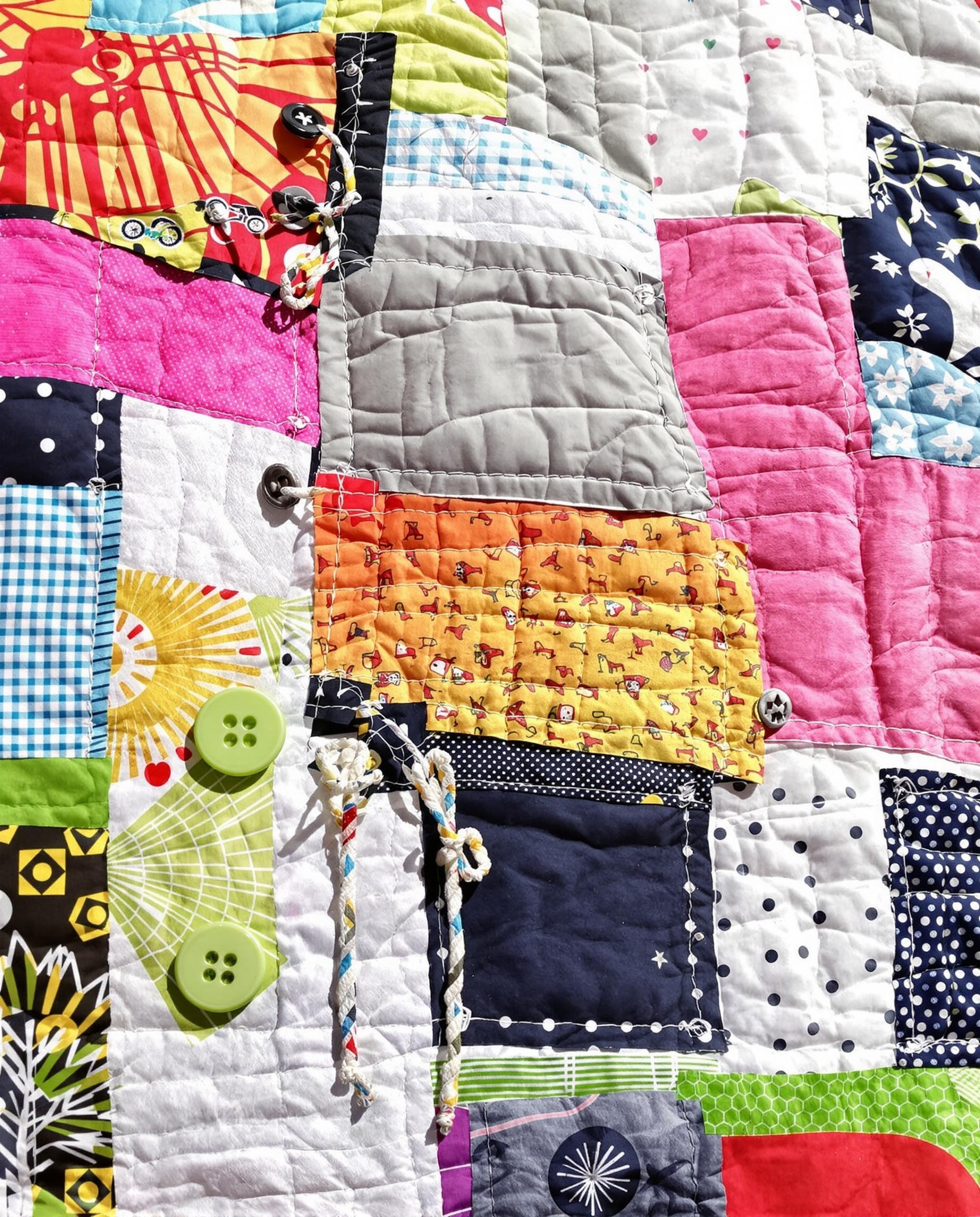 Détails d'un patchwork vélo vert DIY avec quilting, boutons et cordons.