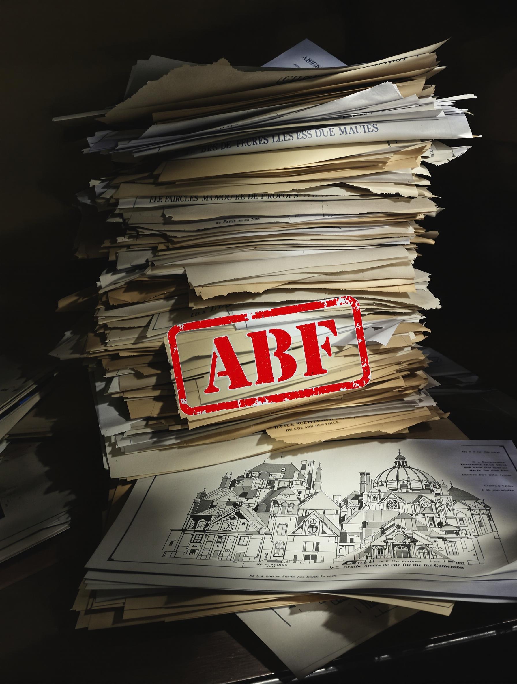 Pile de dossiers administratifs nécessaires pour la rénovation d'une toiture haussmannienne à Paris avec autorisation ABF.