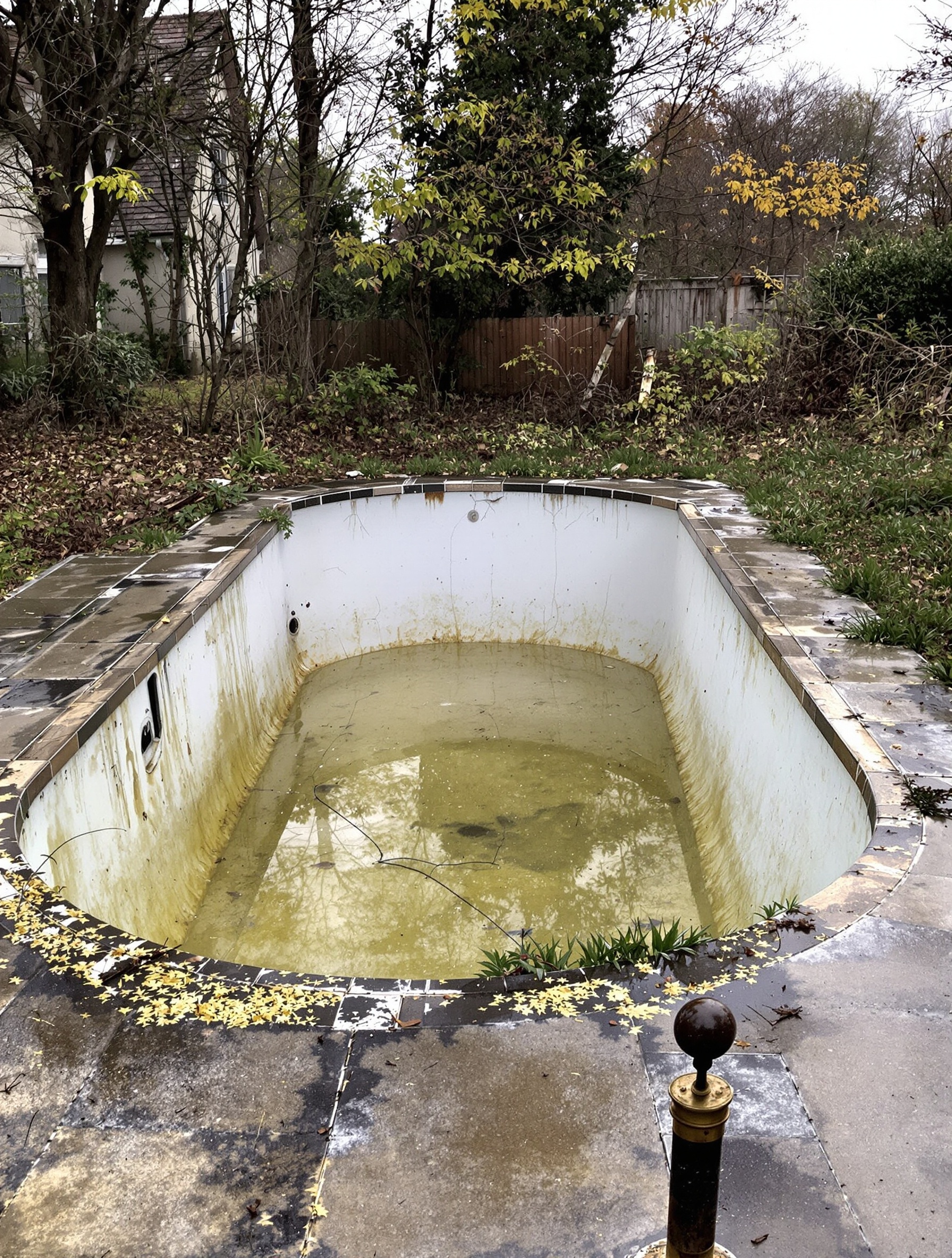 Piscine ancienne à rénover avec liner blanchi, margelles fissurées et carreaux décollés.
