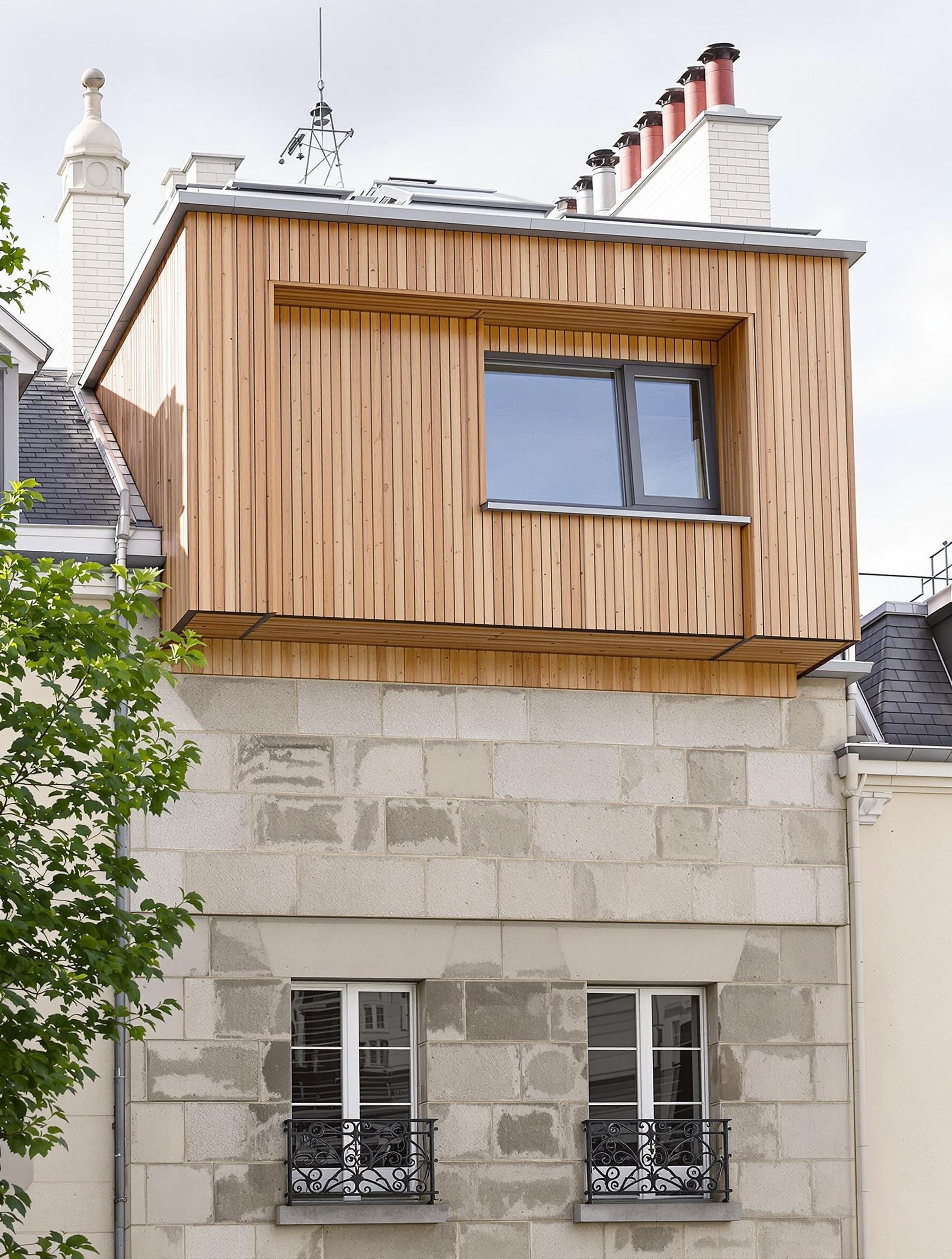 Surélévation bois-zinc dans le XVIIIe arrondissement avec lucarnes patrimoniales et fenêtres de toit.
