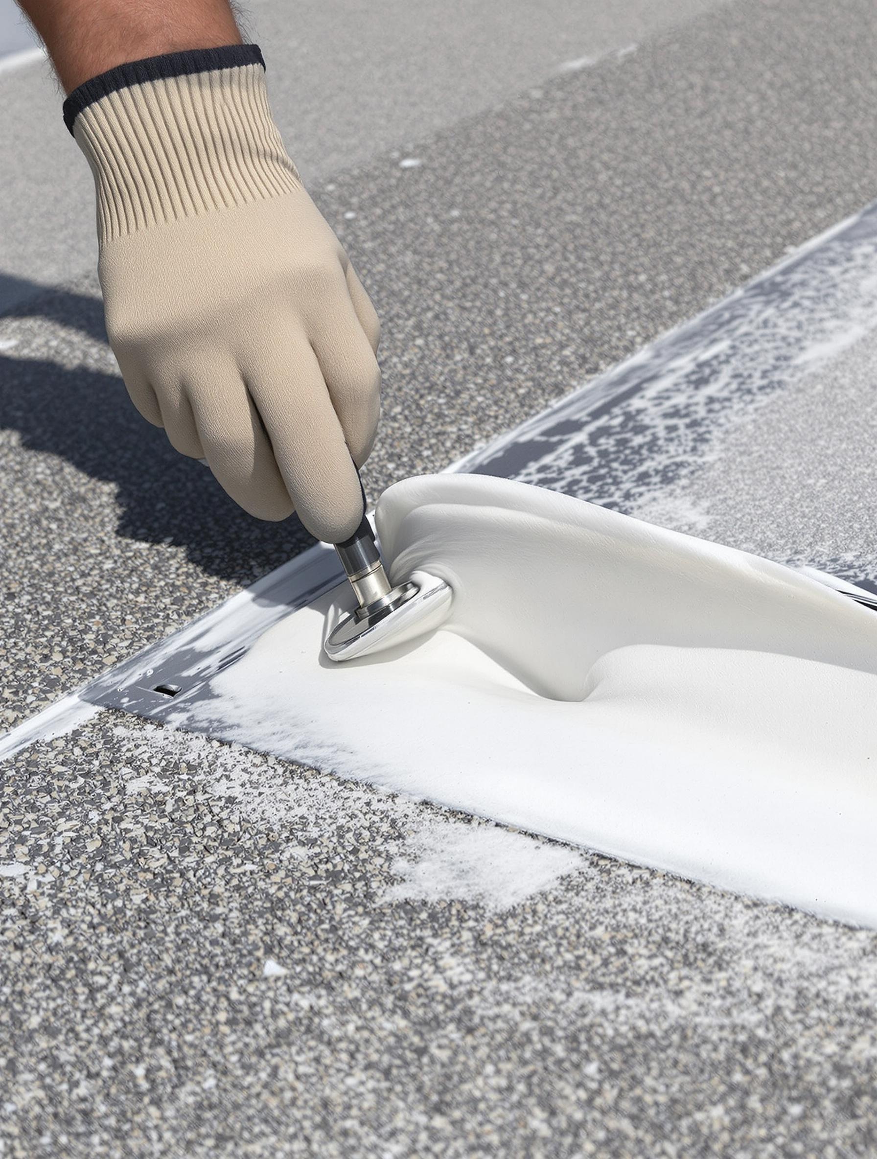 Application de mastic spécial autour d'une évacuation sur toiture terrasse