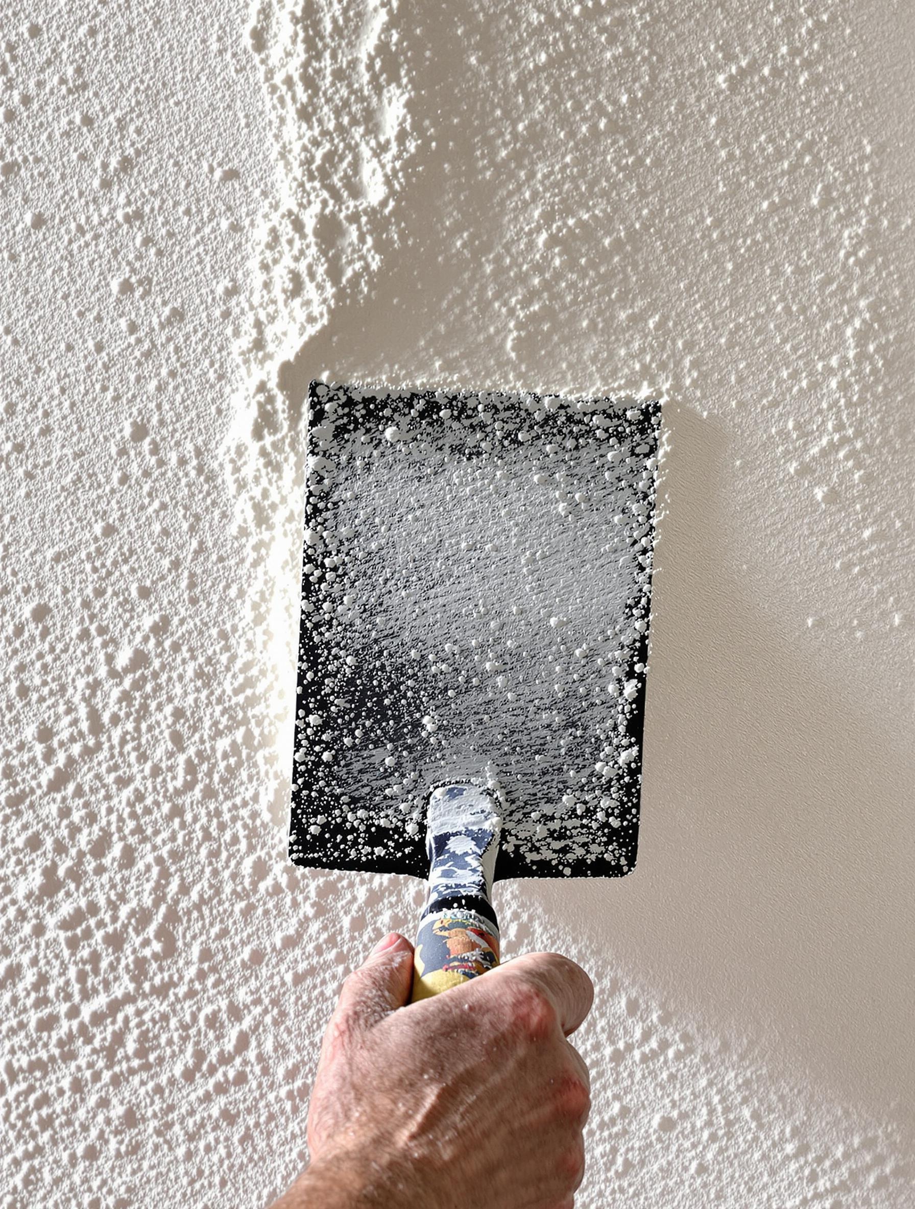 Truelle appliquant une couche de chaux aérienne blanche, texture mate et poreuse